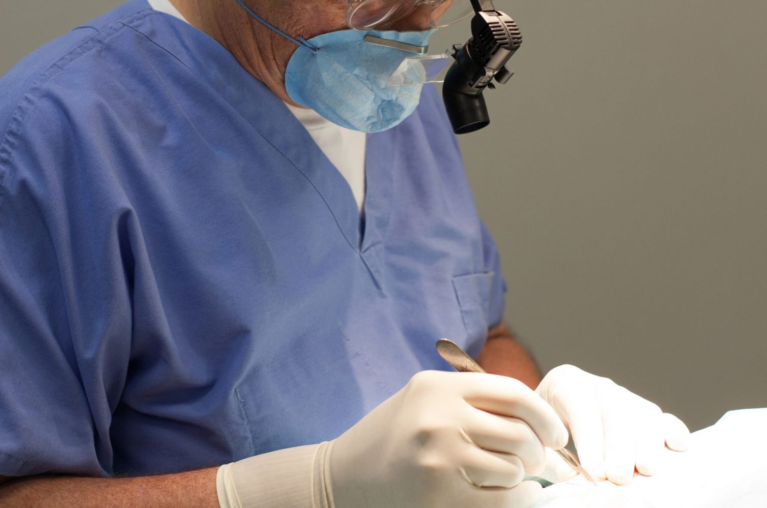 A man wearing a surgical mask, using a scalpel.